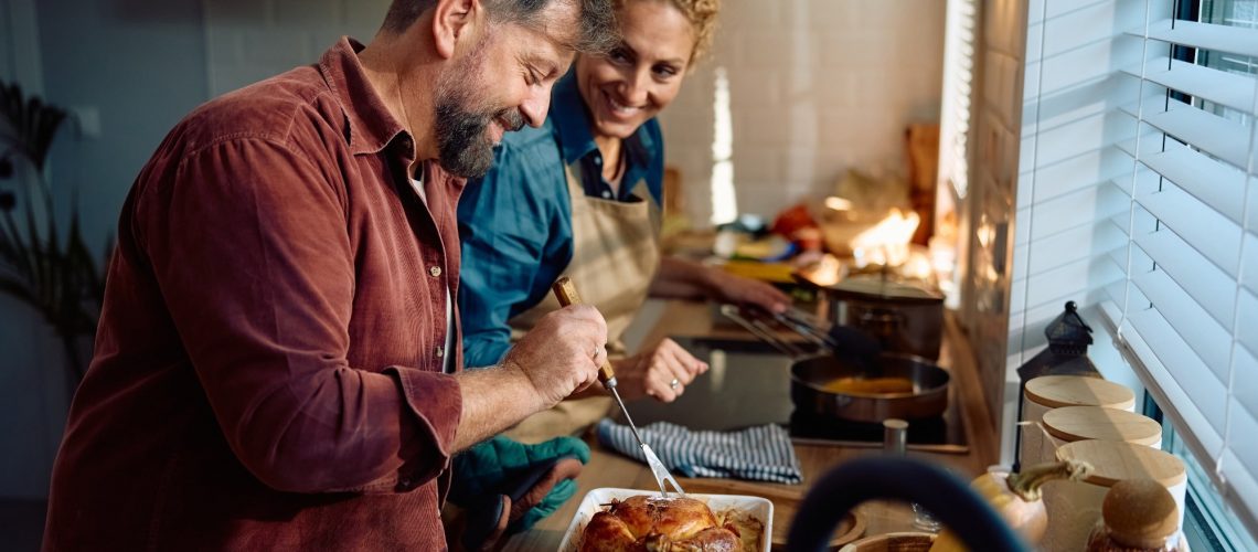 Happy man and his wife preparing roast turkey
