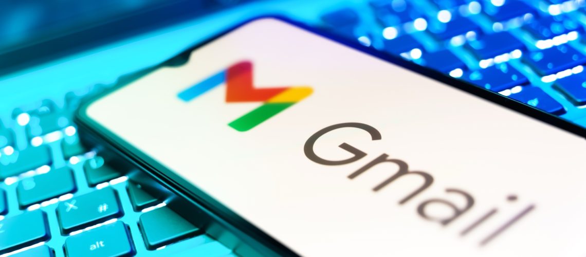 A smartphone with the Gmail logo on it resting on top of a computer keyboard.