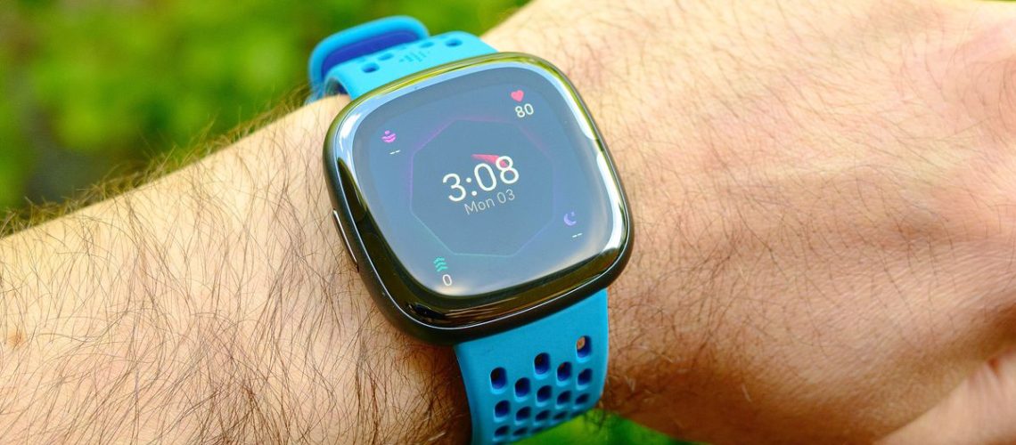 The Fitbit Sense 2 on a blue rubber strap, shown on a user