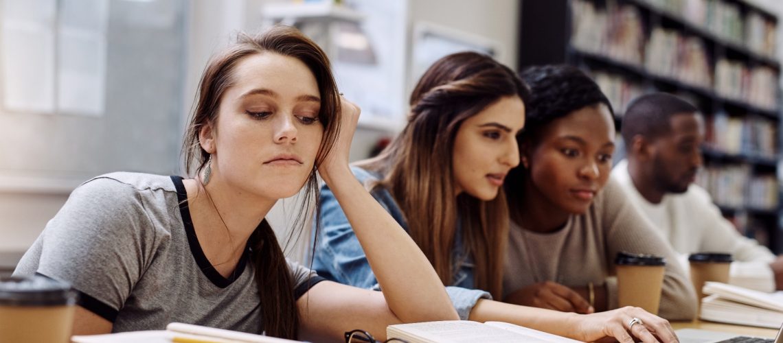 face of unhappy student with books in library