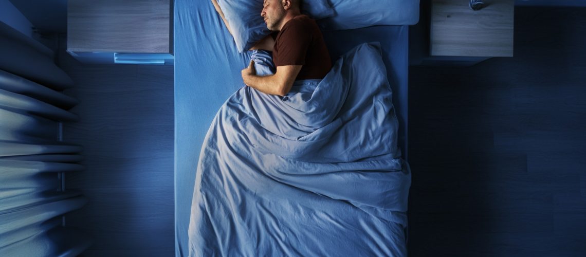Top view of single middle aged man peacefully sleeping alone in bed at night at home