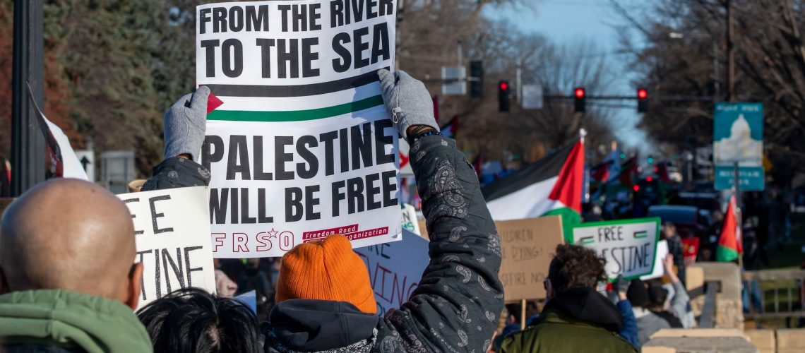 A pro-Palestinian protester holds up a sign reading "From the river to the sea, Palestine will be free" during a rally