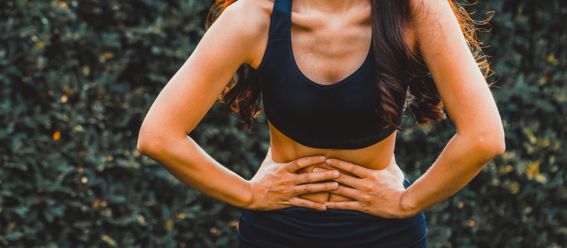 Young sport woman having pain at her stomach.