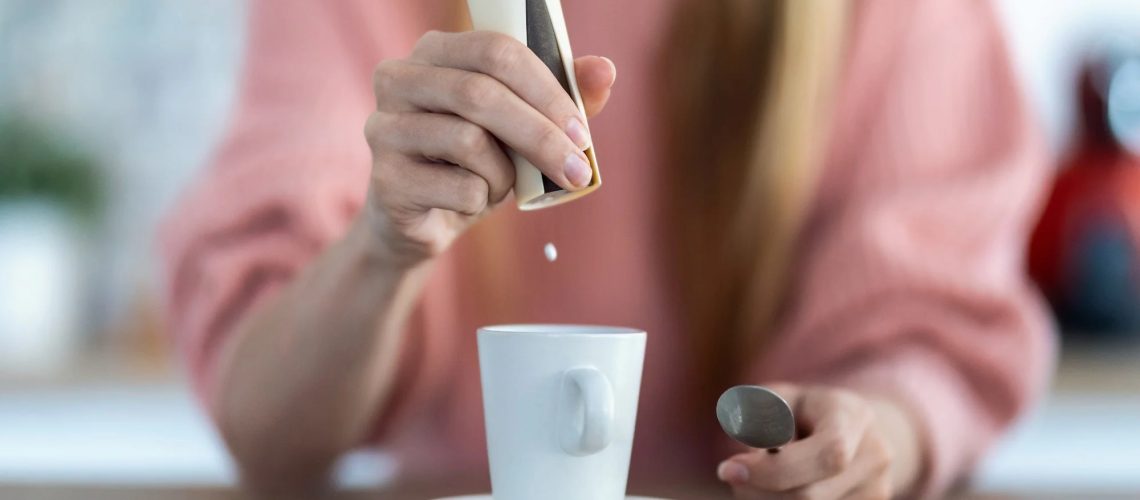 Close-up of woman hand throwing saccharin pills on coffee cup in the kitchen at home.