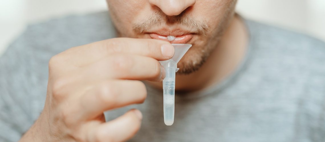 man spitting with mouth through funnel in plastic tube to collect sample