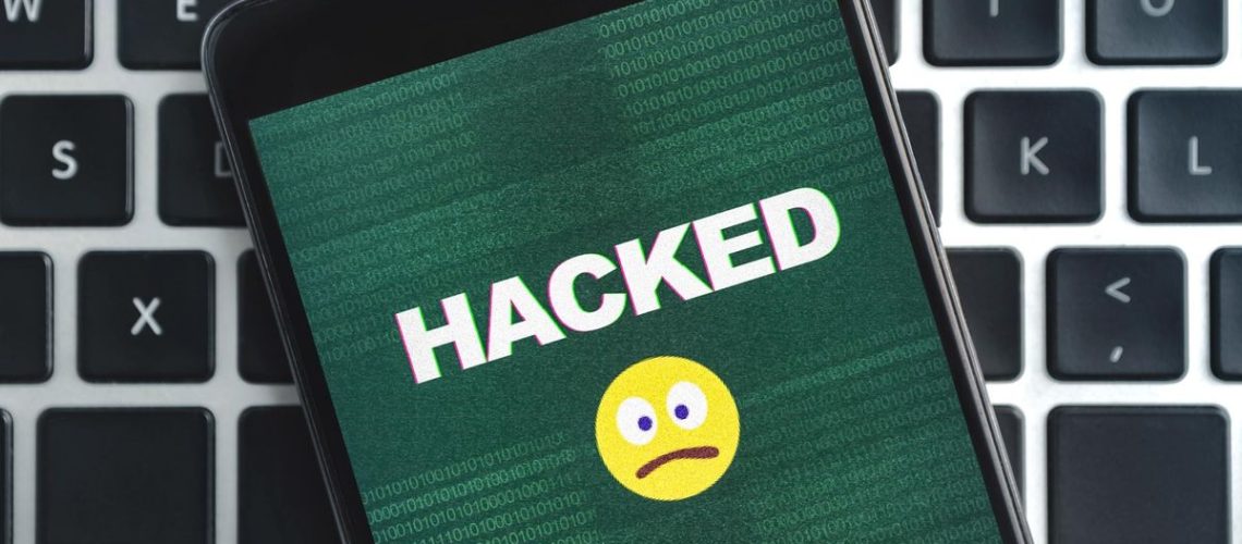 An emoji on a hacked phone on top of a laptop