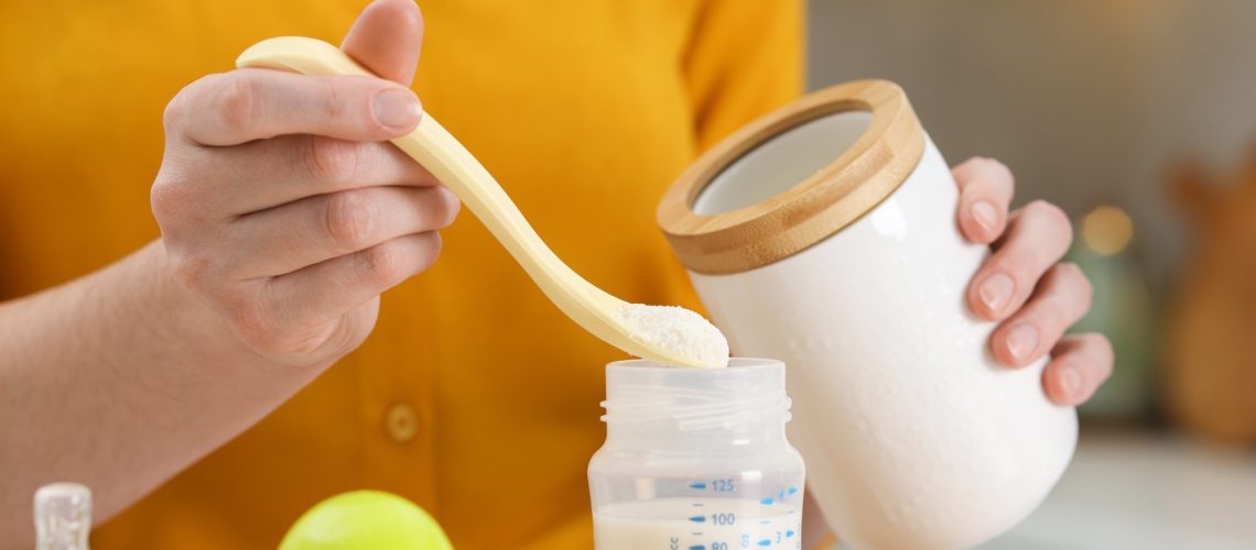 Mother making baby formula in feeding bottle