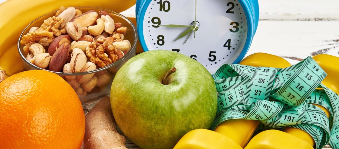 Alarm clock, dumbbells and apple