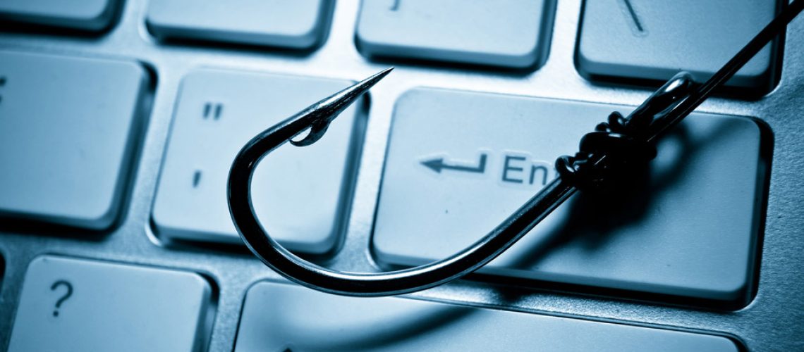 A fishing hook resting on a laptop keyboard.