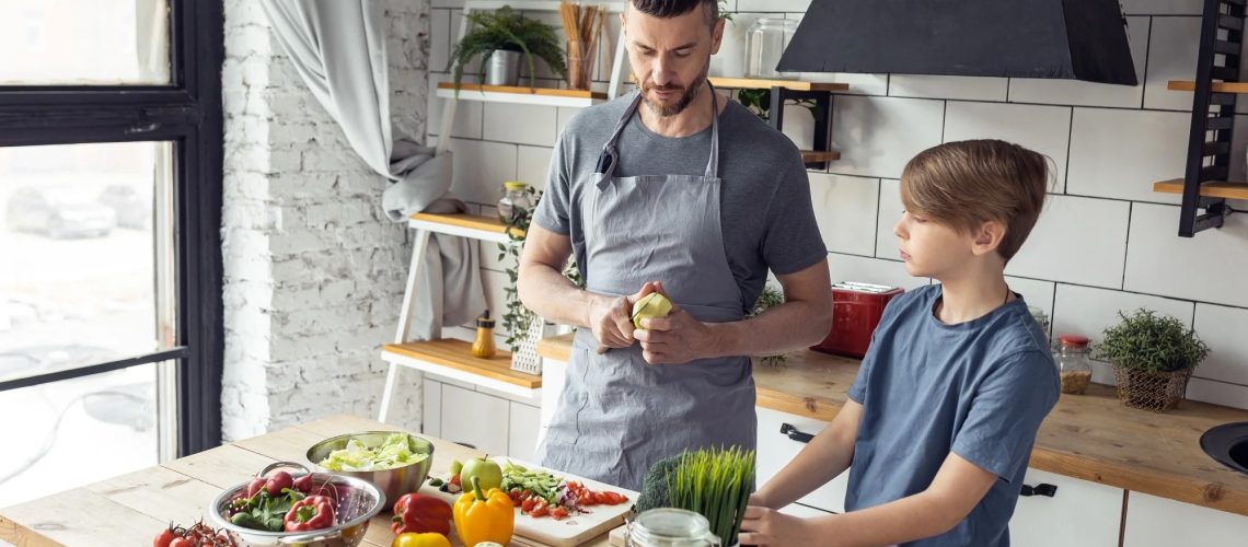 Father and son cooking vegetables in kitchen