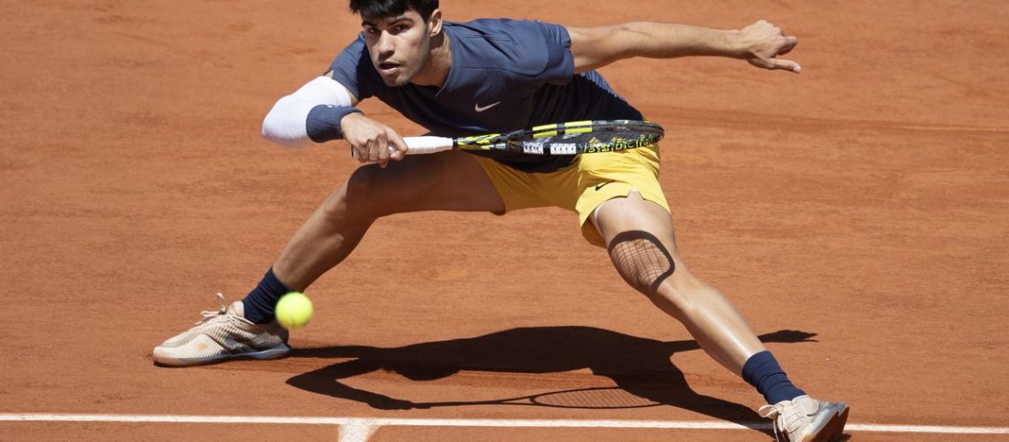 Carlos Alcaraz gets low for a return shot at the French Open 2024