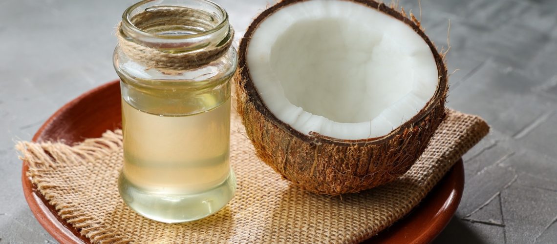 Coconut Oil in glass jar with Coconut cut open in half.