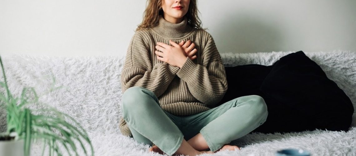 Woman practicing pranayama in lotus position on bed