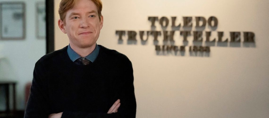 Ned (Domhnall Gleeson) poses, arms crossed, in front of the Toledo Truth Teller sign in a scene from Peacock's "The Paper"