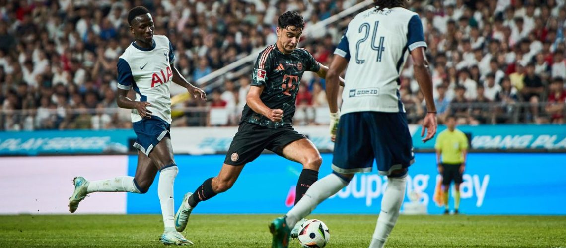 Aleksandar Pavlovic, in black shorts and shirt, dribbles through the Spurs lines in the Tottenham vs Bayern Munich live stream.