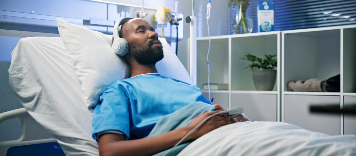 Black man, relax and sleep with headphones in hospital bed