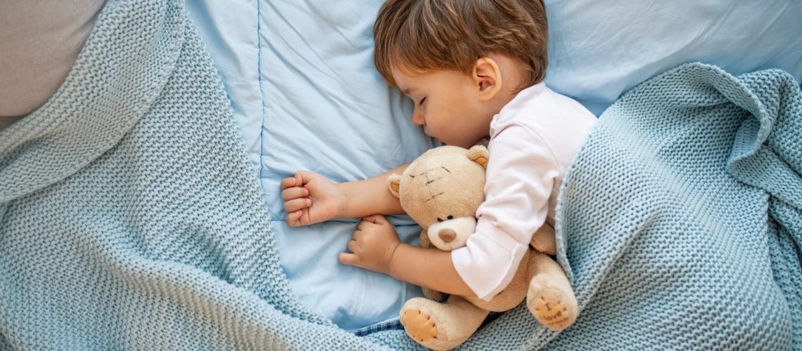 Photo of young boy sleeping together with teddy bear.