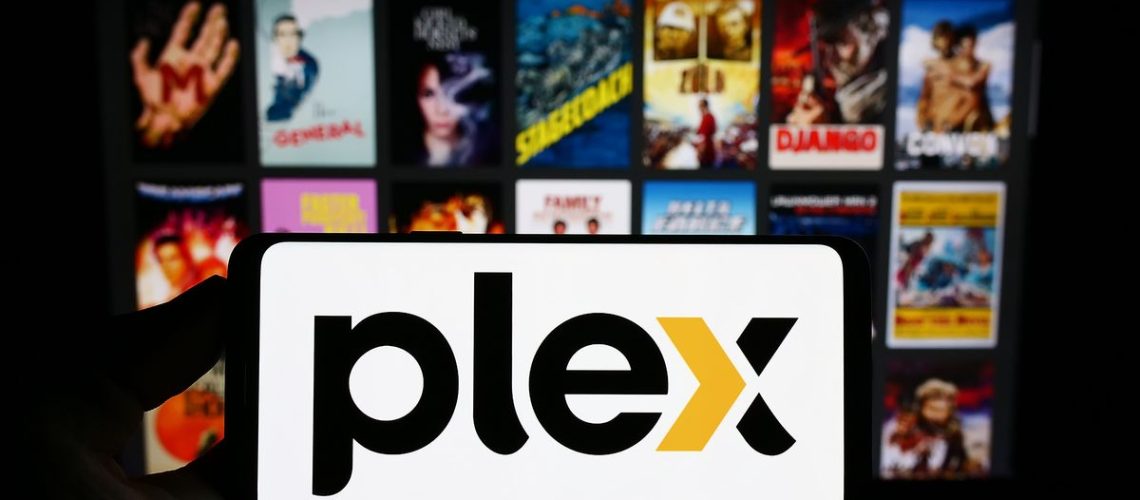A phone with the Plex logo in front of an out-of-focus background of movie posters