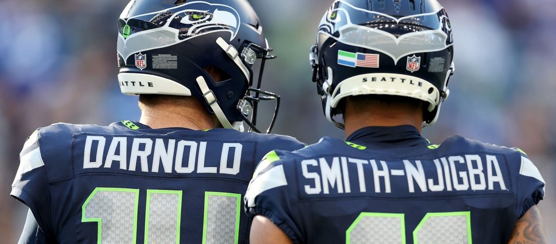 Sam Darnold #14 and Jaxon Smith-Njigba #11 of the Seattle Seahawks standing side-by-side during an NFL game.