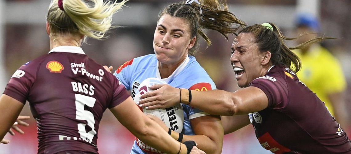 Blues player is tackled by two Maroons in the Women