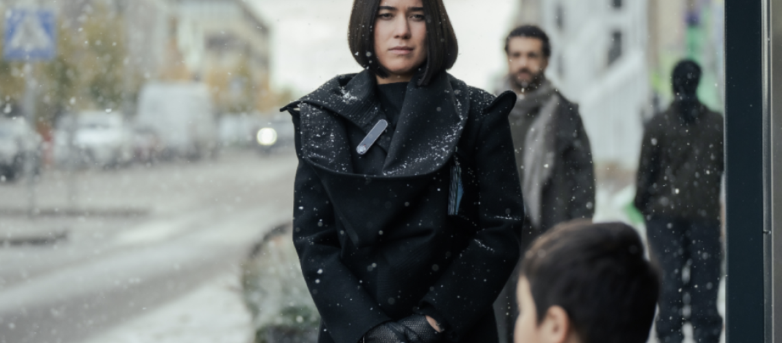 Smilla Jaspersen (Filippa Coster-Waldau) gazes at a child in the foreground, with Rahid Youseffi (Elyas M'Barek) in the background in Smilla's Sense of Snow