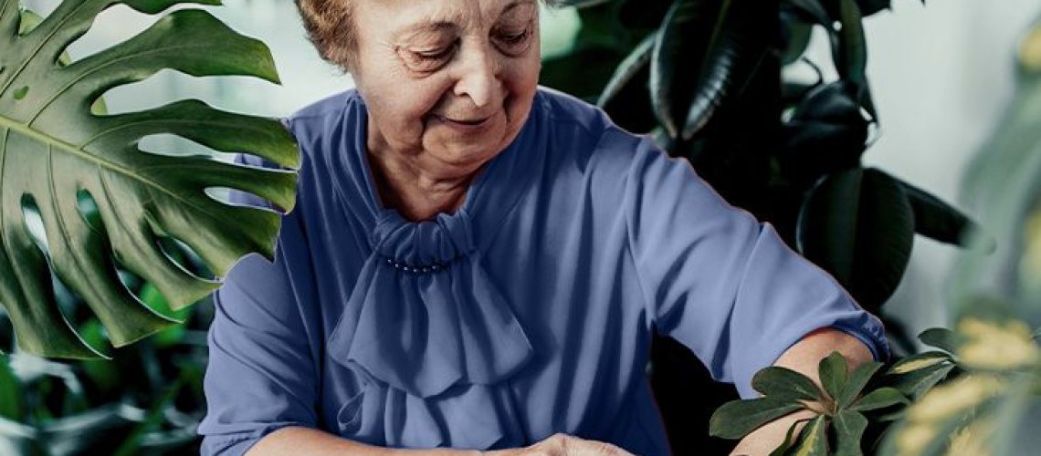 older woman surrounded by tall plants checking smartwatch