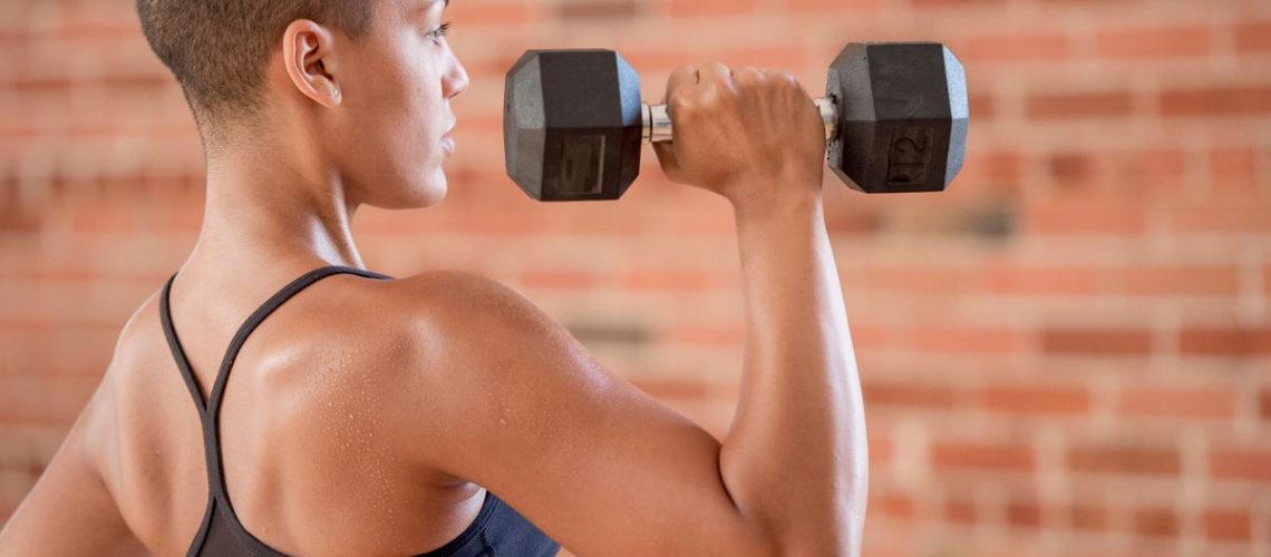 a woman lifting a dumbbell above her shoulder