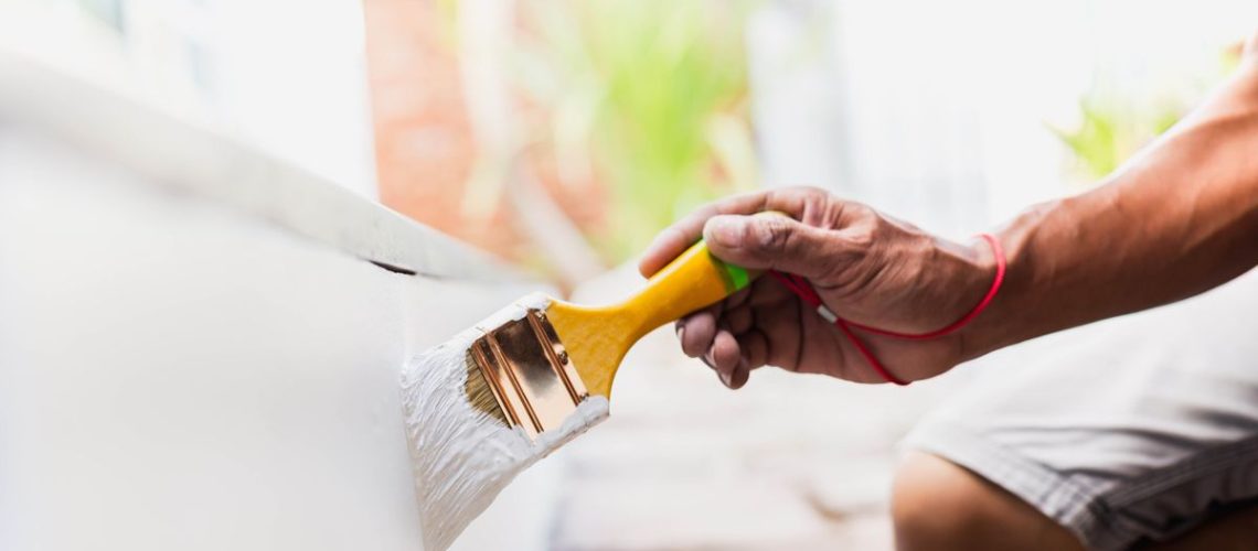 Man painting exterior wall white