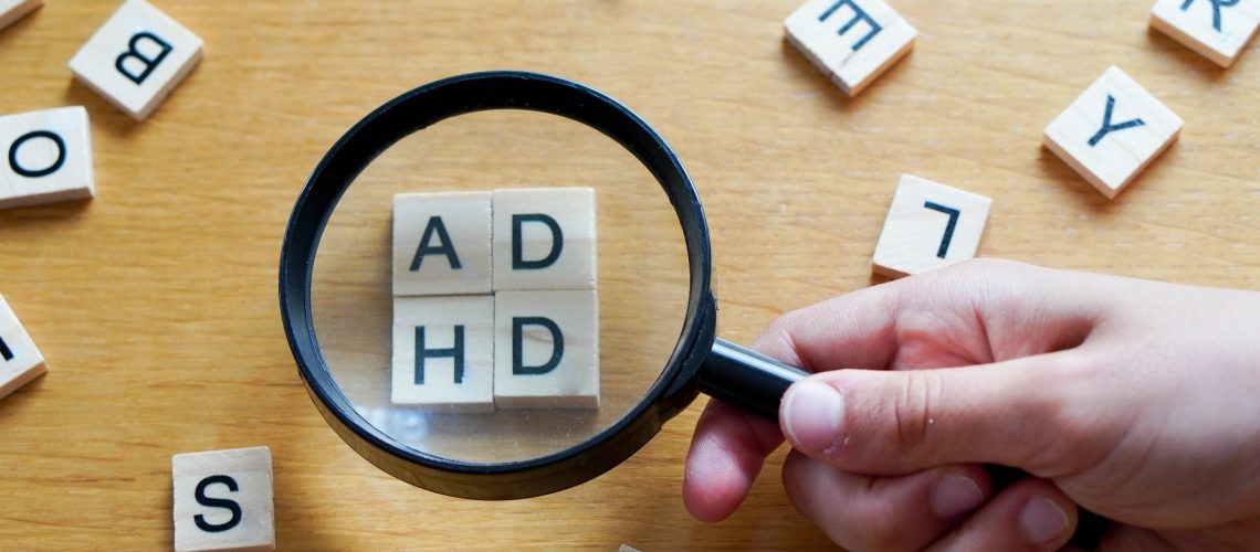 magnifying glass with wooden letters ADHD.