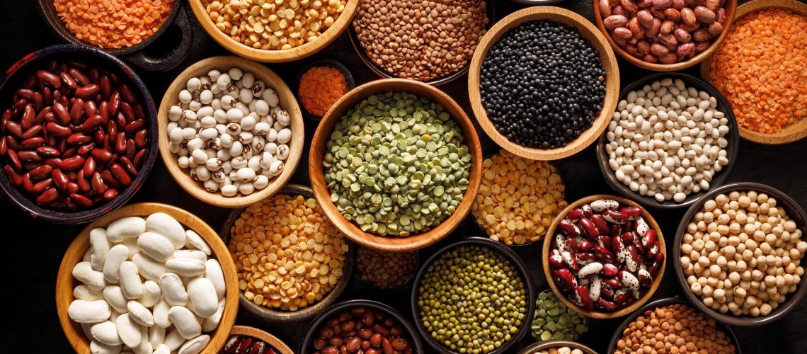 Legumes, a set consisting of different types of beans, lentils and peas on a black background, top view