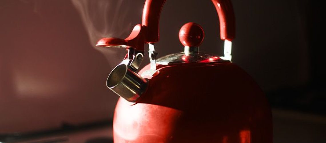 red kettle letting out steam on a stove