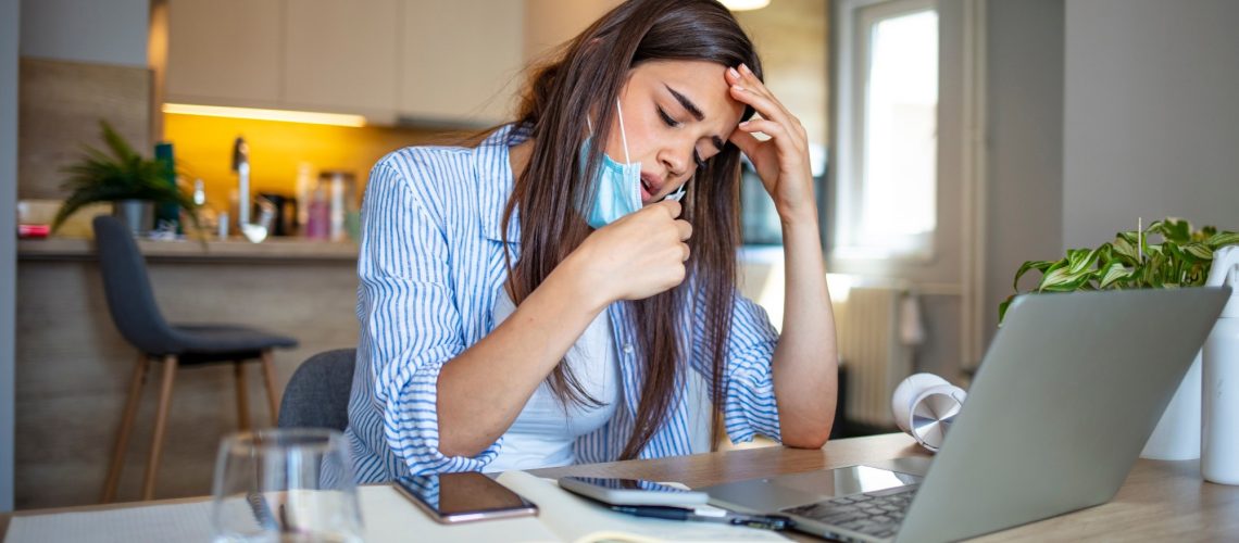Woman working in the office and having difficulties breathing with face mask