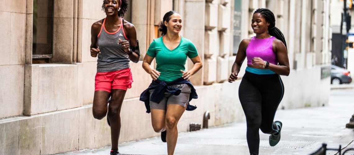 three women running down a street together