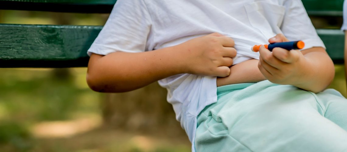 School boy with diabetes injecting insulin