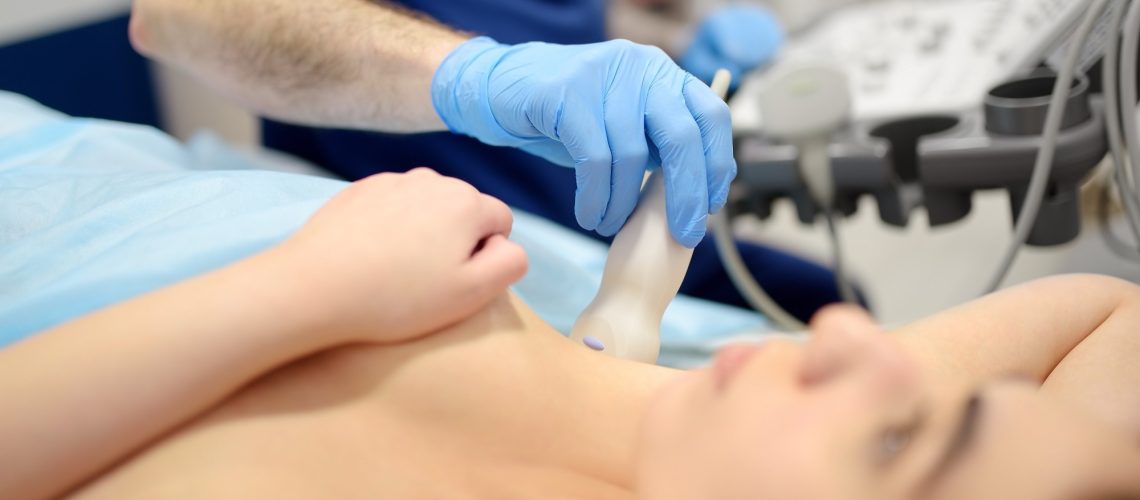 Mammologist doctor examines a woman breasts and lymph nodes using ultrasound