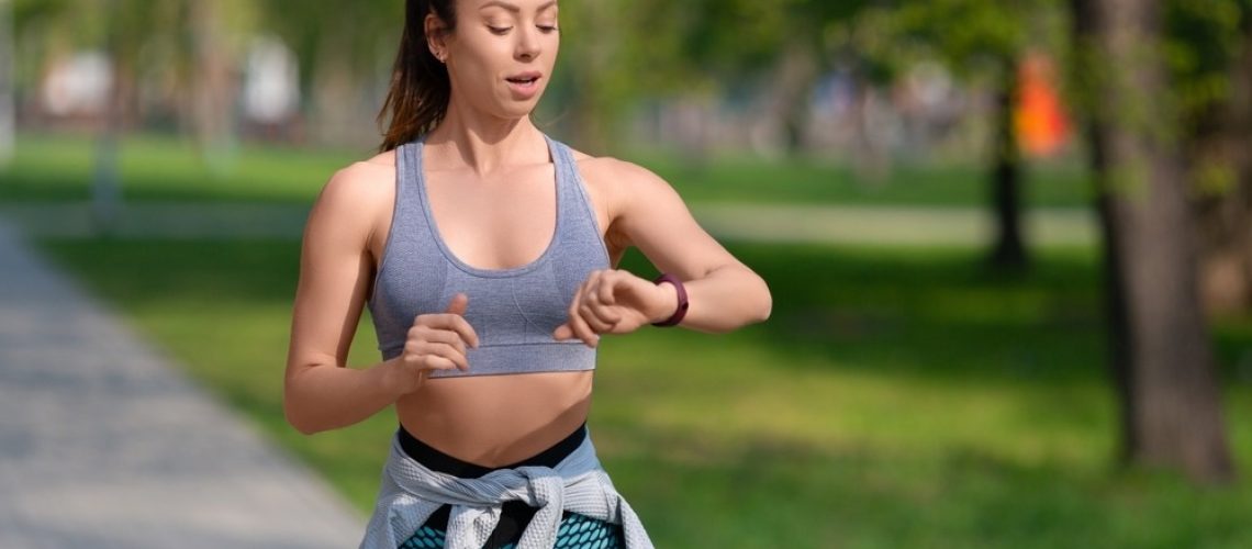Woman checks her pulse after jogging workout in the park.