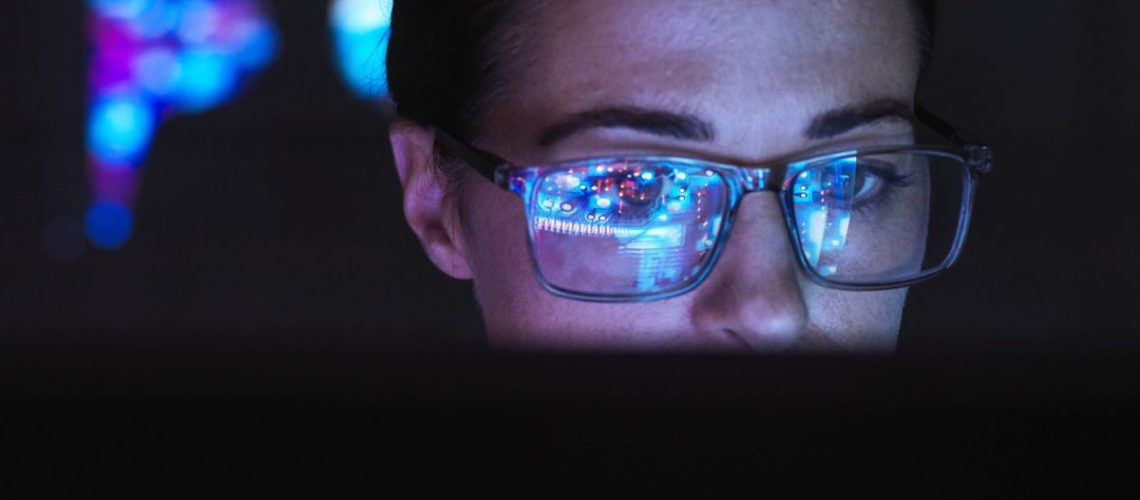 Engineer designing AI technology with reflection on eyeglasses