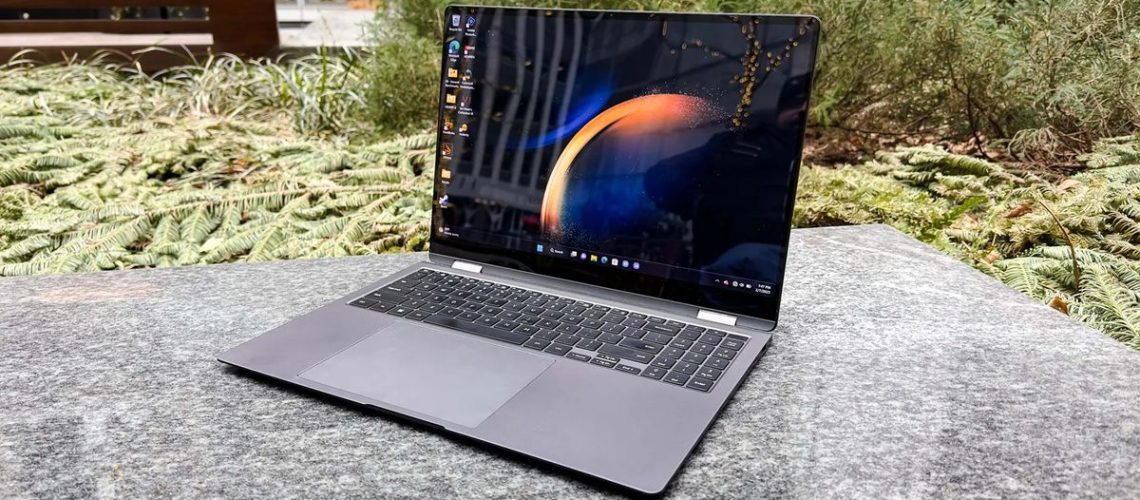 A laptop sitting on a backyard table with plants in the background.