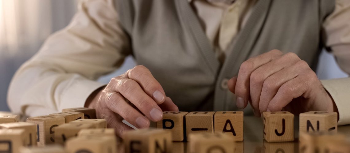 Male pensioner trying to make word of wooden cubes.