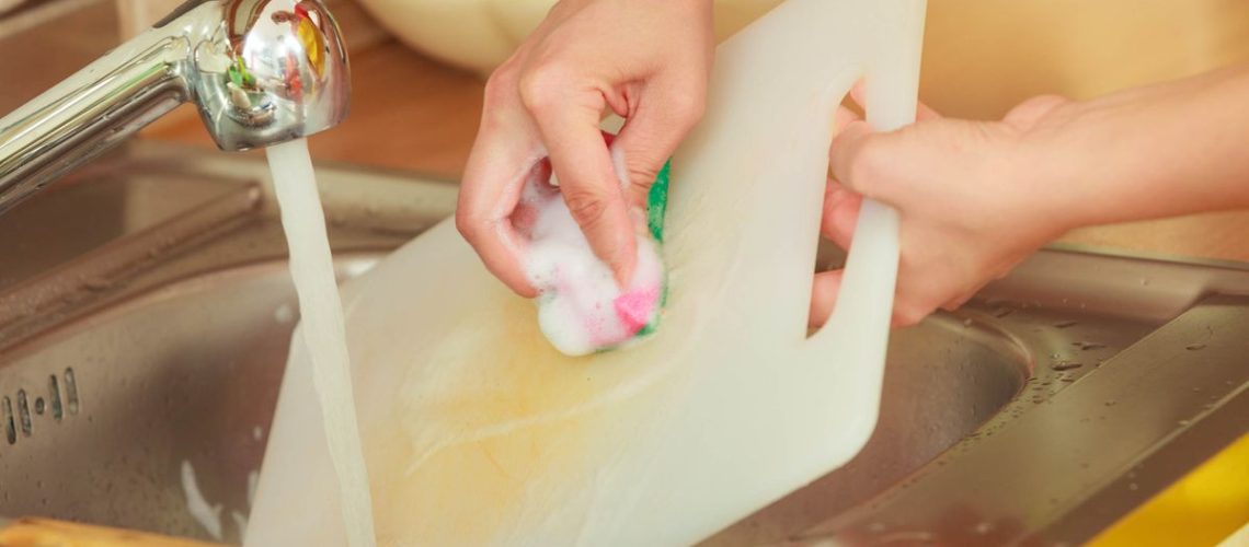 Woman washing a plastic cutting board