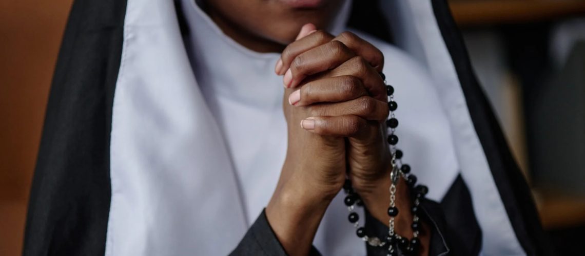 Nun praying with hands and rosary