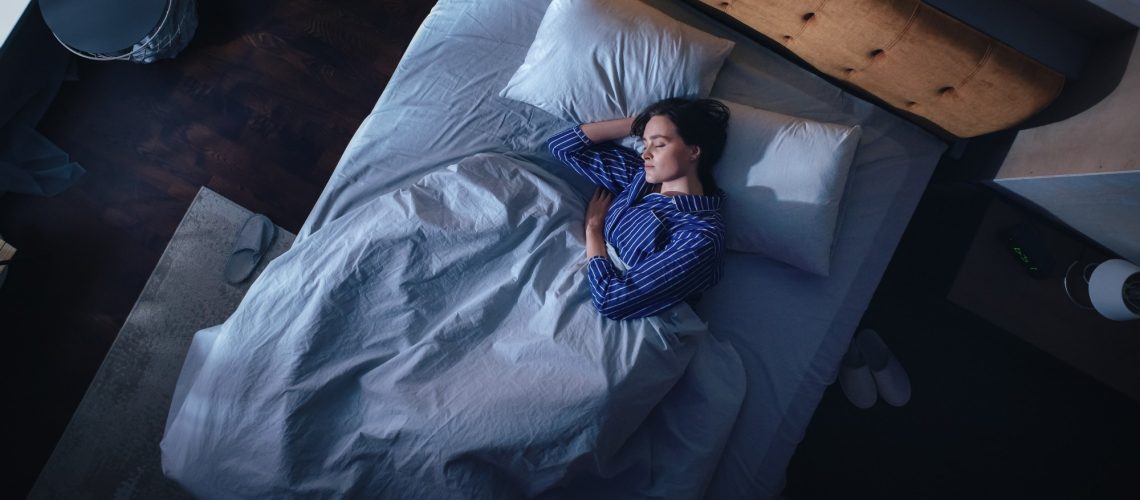 Top View of Young Woman Sleeping on a Bed in Her Bedroom at Night