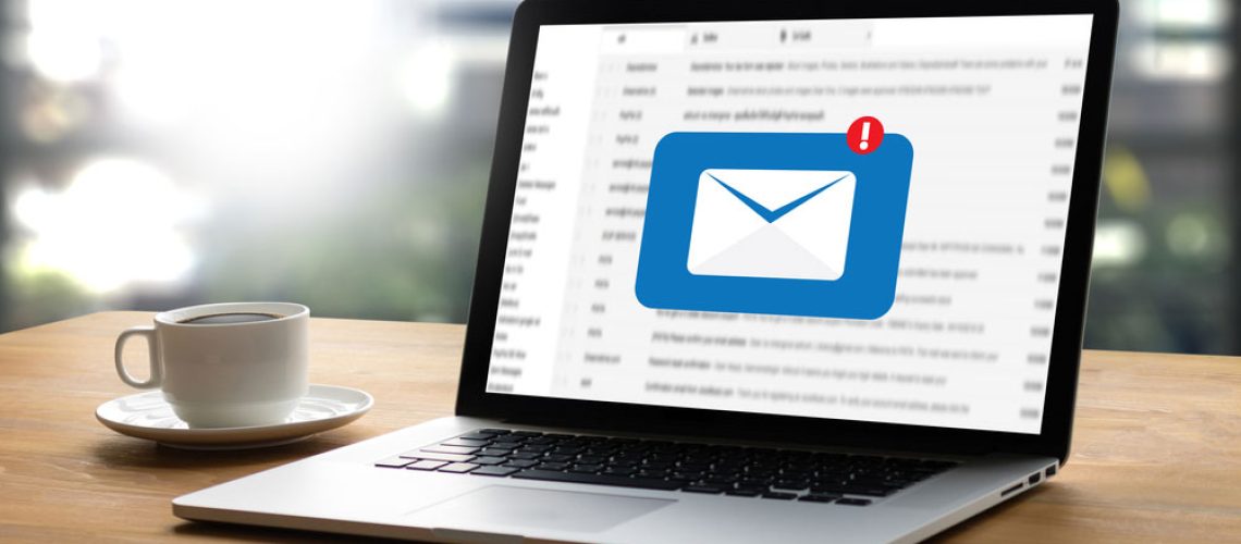 An email inbox displayed on the screen of a laptop, next to a cup of coffee.