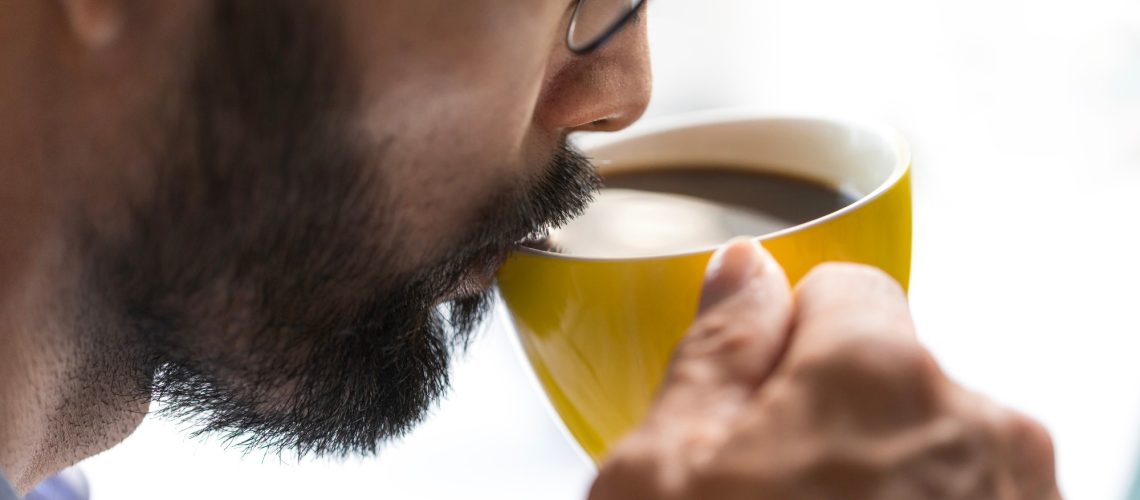 Close-up of a bearded business man drinking coffee in the office, white background
