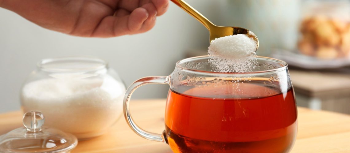 Woman adding sugar into aromatic tea