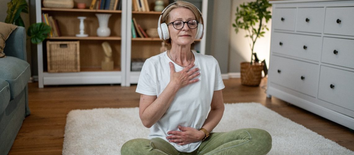 Elderly woman sat on floor doing simple exercise and taking deep breath