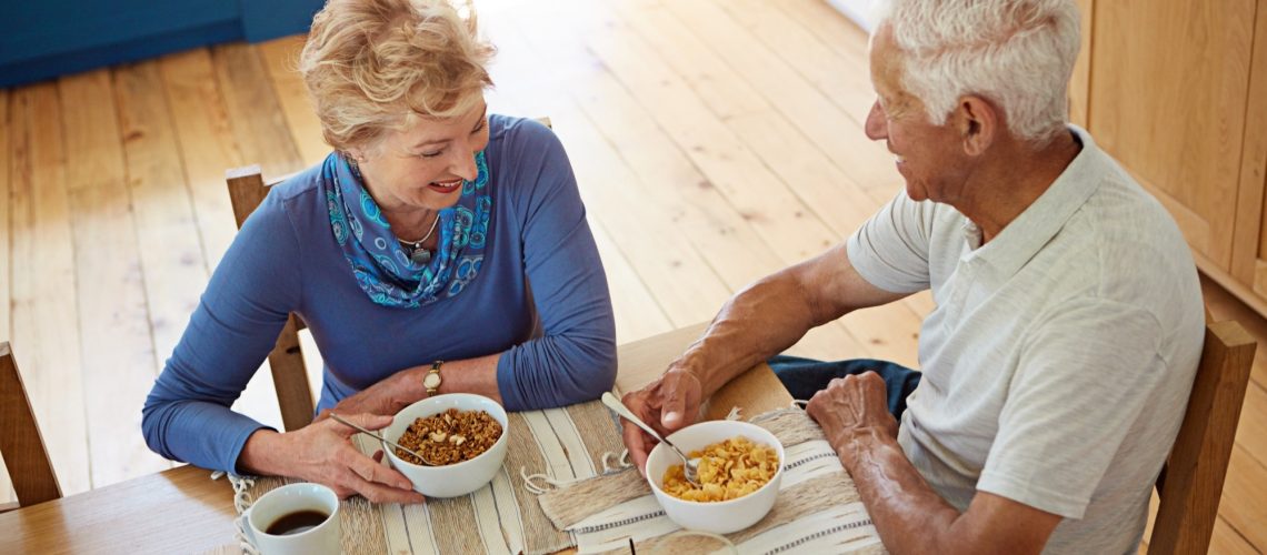 Elderly couple eating at breakfast in dining room