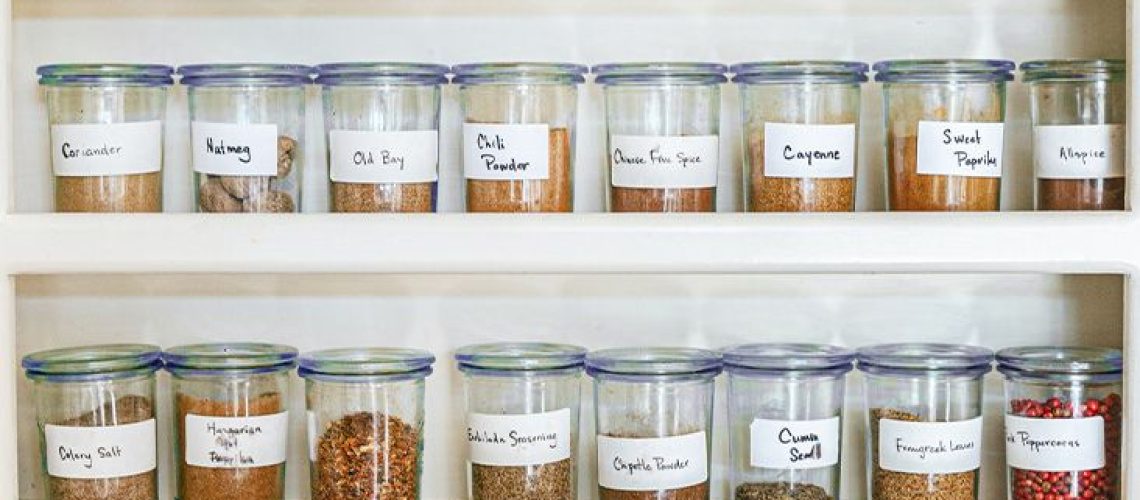 A variety of dry spices in glass jars on shelves
