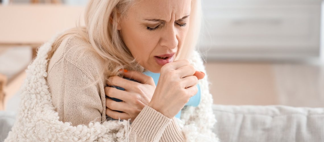 Ill mature woman coughing at home, closeup