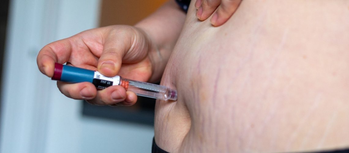 Overweight woman applying diabetes medicine injection into her belly